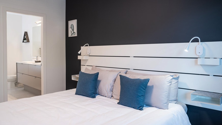 Doppelzimmer im Stoked Penthouse Revelstoke mit Holzlatten-Kopfteil und schwenkbaren Wandleuchten.