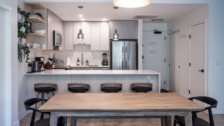 Offene Küche im Stoked Penthouse Revelstoke mit Kücheninsel, Barhockern und angrenzendem Essbereich.