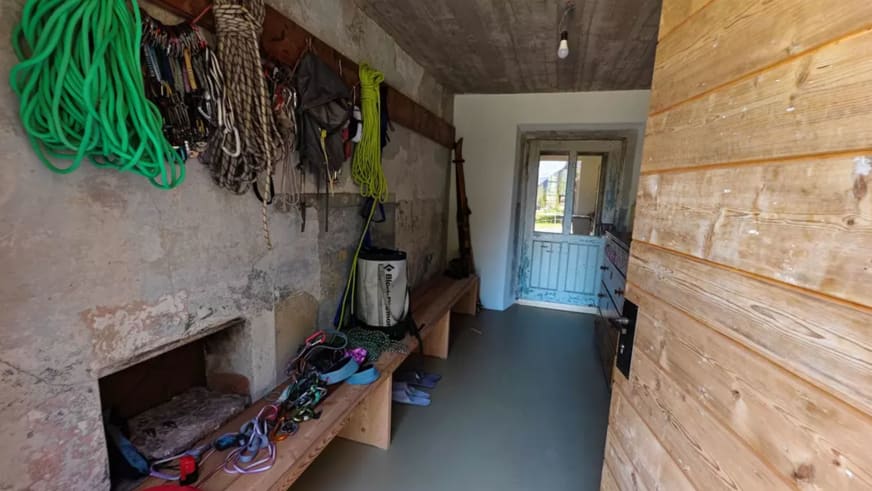 Im Ausrüstungsraum der ANAS126 Lodge hängen Kletterseile, Gurte und Karabiner an der Steinwand zur Aufbewahrung.
