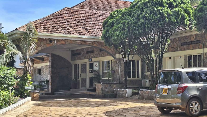 Haupteingang des Entebbe Palm Hotel mit charakteristischem Natursteinbogen und rotem Terrakotta-Dach in Uganda.
