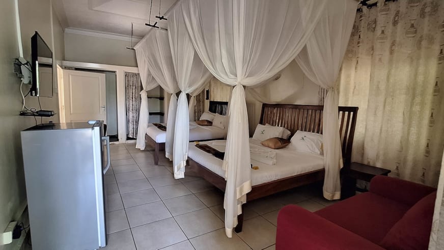 Zweibettzimmer im Entebbe Palm Hotel mit zwei Himmelbetten, Moskitonetzen und moderner Ausstattung inklusive Kühlschrank.