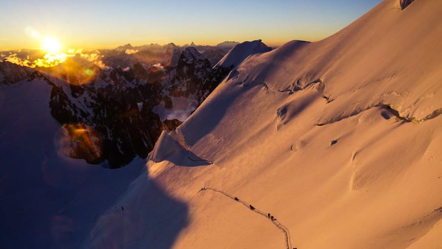Hochtour am Mont Maudit: Bergsteigergruppe steigt in Einerseilschaft über steilen Schneehang Richtung Mont Blanc auf.
