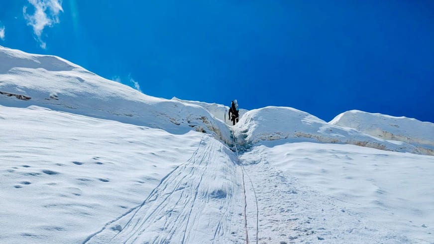 Expedition am Pik Lenin: Höhenbergsteiger steigt gesichert am Seil durch einen steilen Schneeeinschnitt auf.
