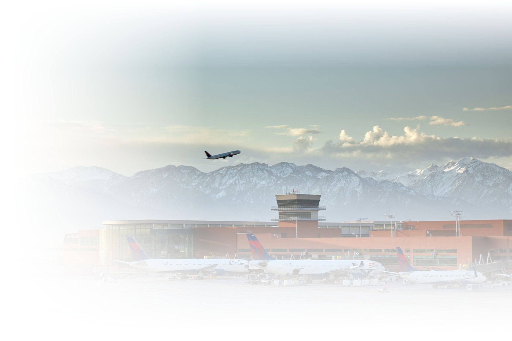 A photo of a plane taking off from the SLC Airport with the Wasatch Mountains in the background