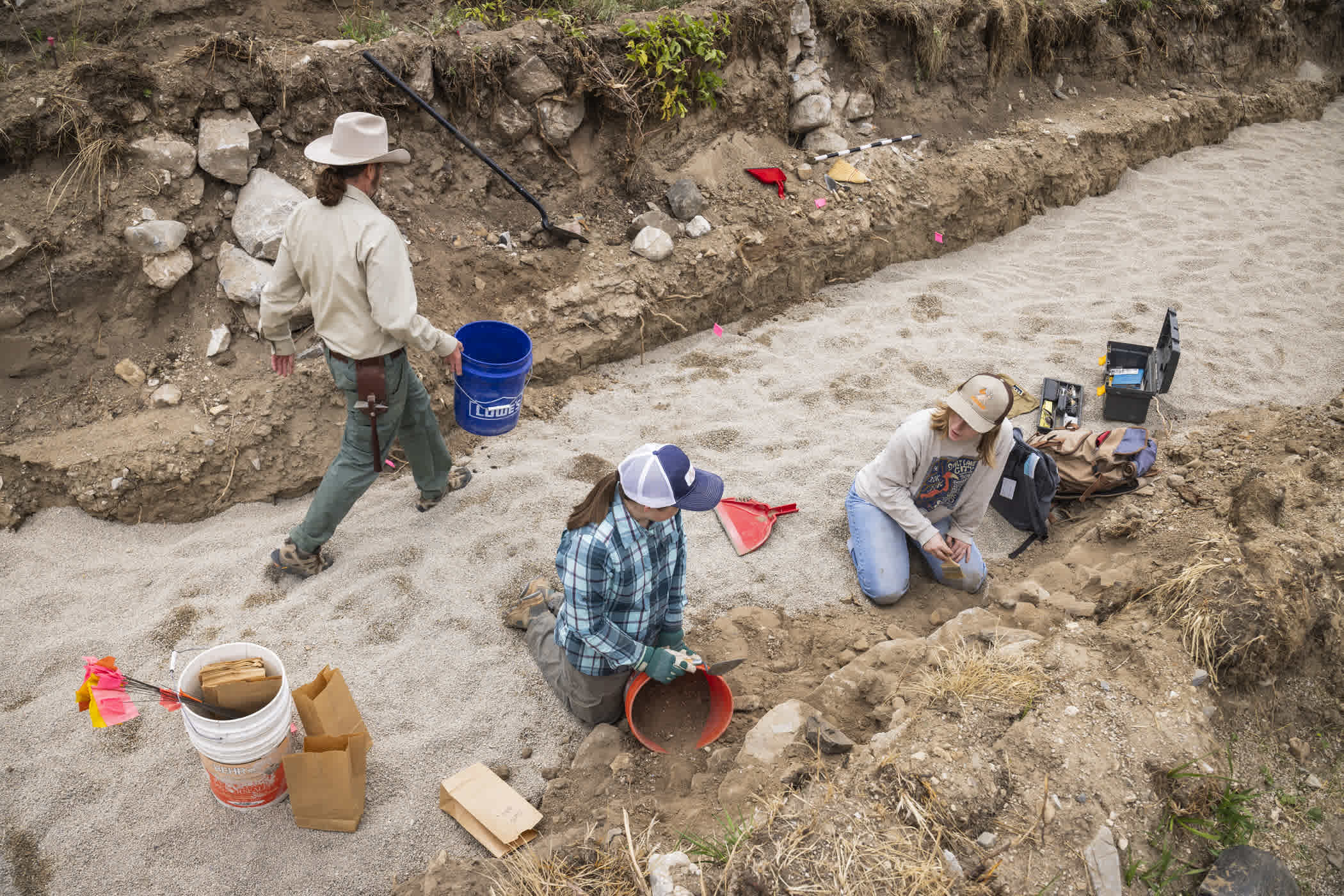 Archaeologist uncovering the stone foundation | Photo: Rocko Menzyk
