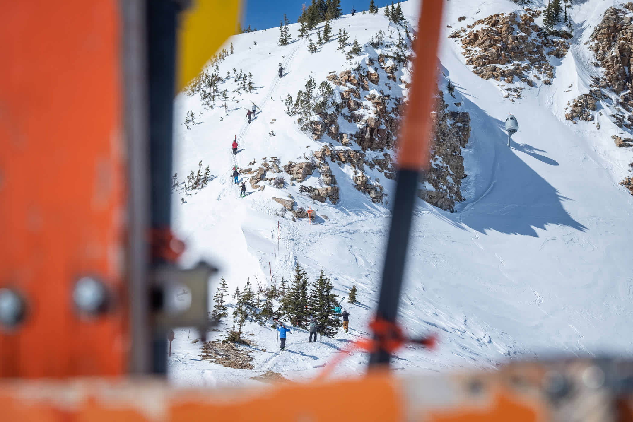 Skiers use a bootpack to hike to the summit of Mount Baldy on a sunny day
