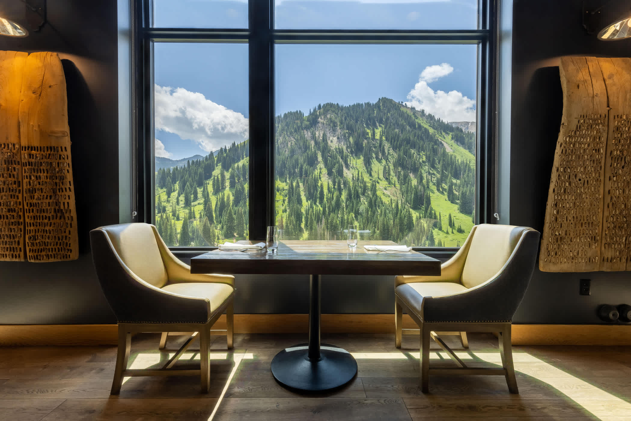 A fine dining table for two in a restaurant with a scenic view of mountains beyond the window