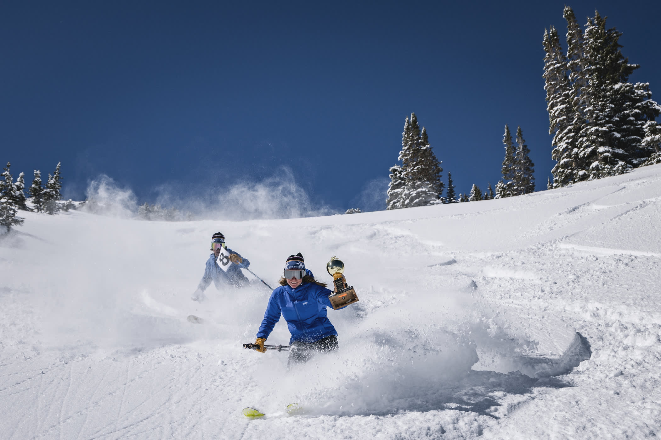 Skiers and a trophy skiing down a powder snow slope