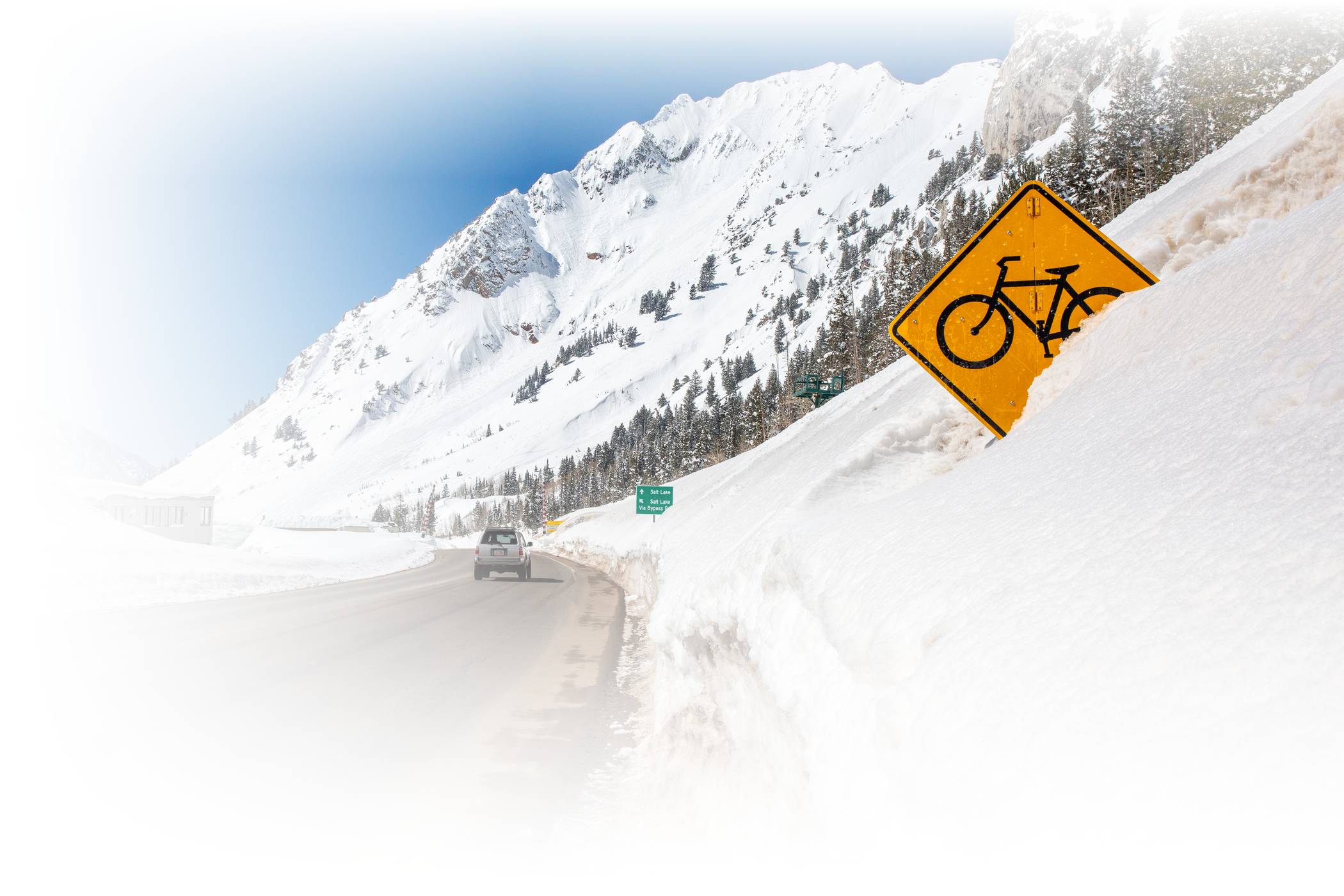 A car drives down Little Cottonwood Canyon on a sunny winter day