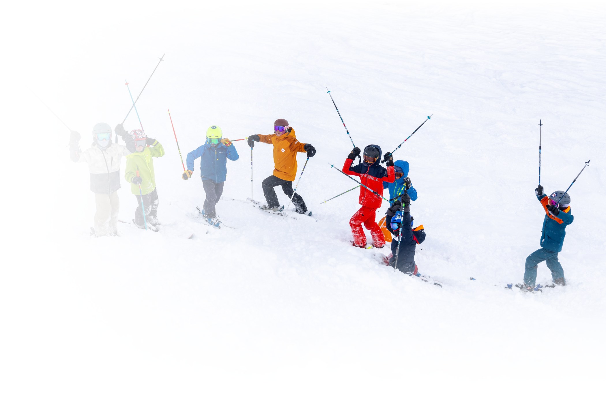 young kids in helmets and googles skiing together