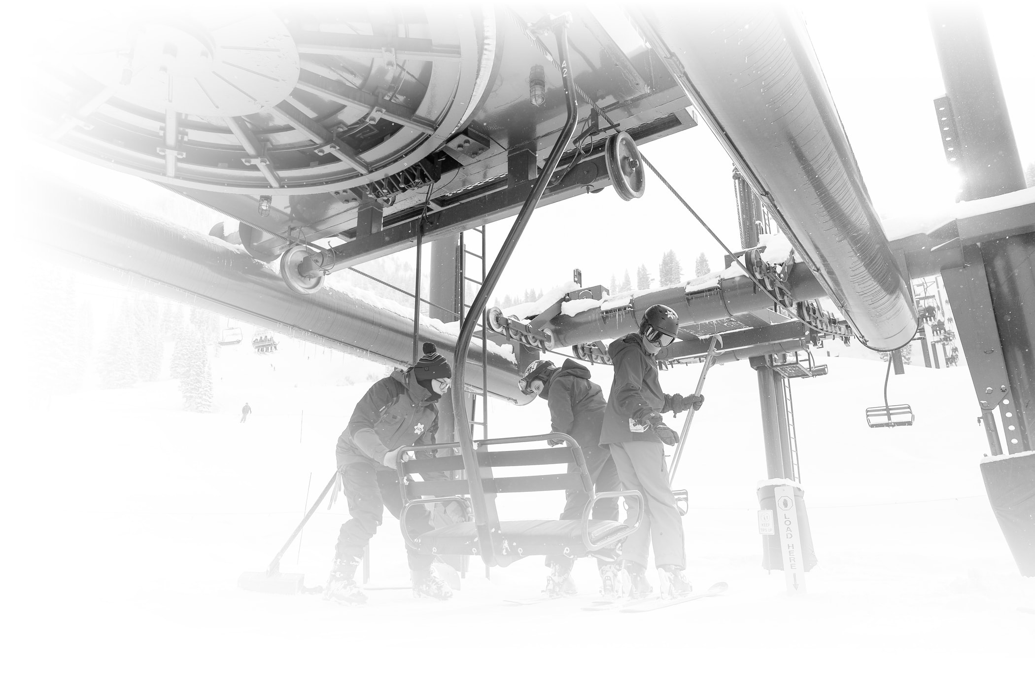An Alta Ski Area employee helps two skiers load the Wildcat chair
