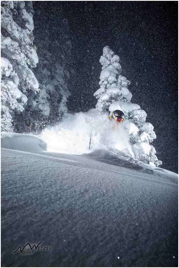 Skier skiing deep powder at night with clear starry skies