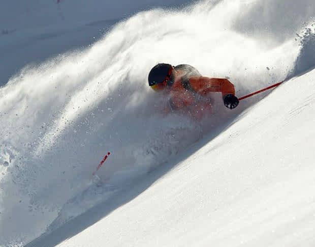 Skier with black helmet making turn in fresh deep snow