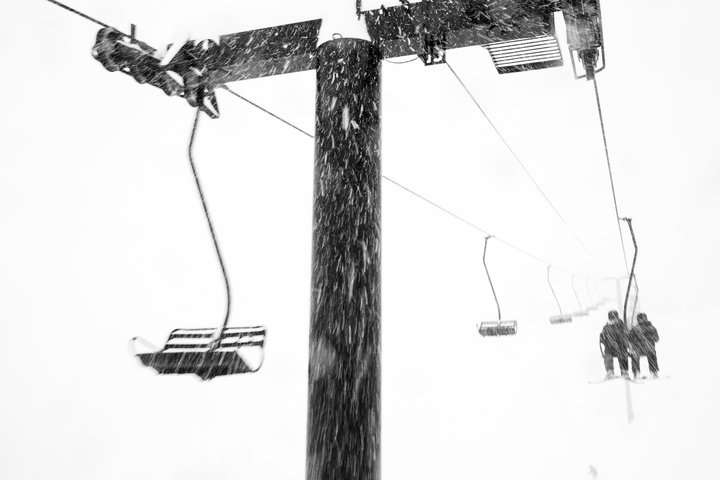 Skiers ride Wildcat lift in a blizzard