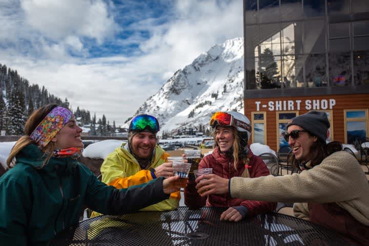 Group of young skiers "cheersing" beers on outside deck of Goldminer's Daughter's cafe