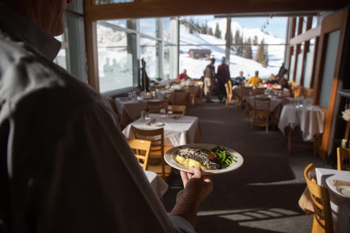 Waiter brings food to skiers at Collins' Grill