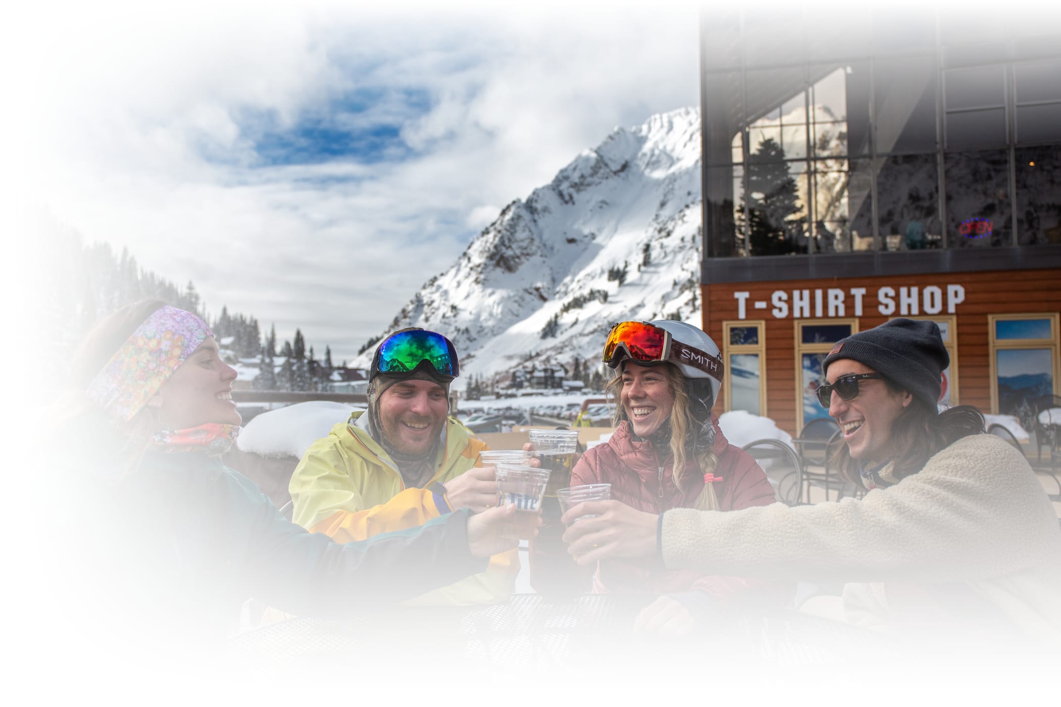 Young skiers "cheersing" beers on sunny porch of Goldminer's daughter's Slopeside cafe