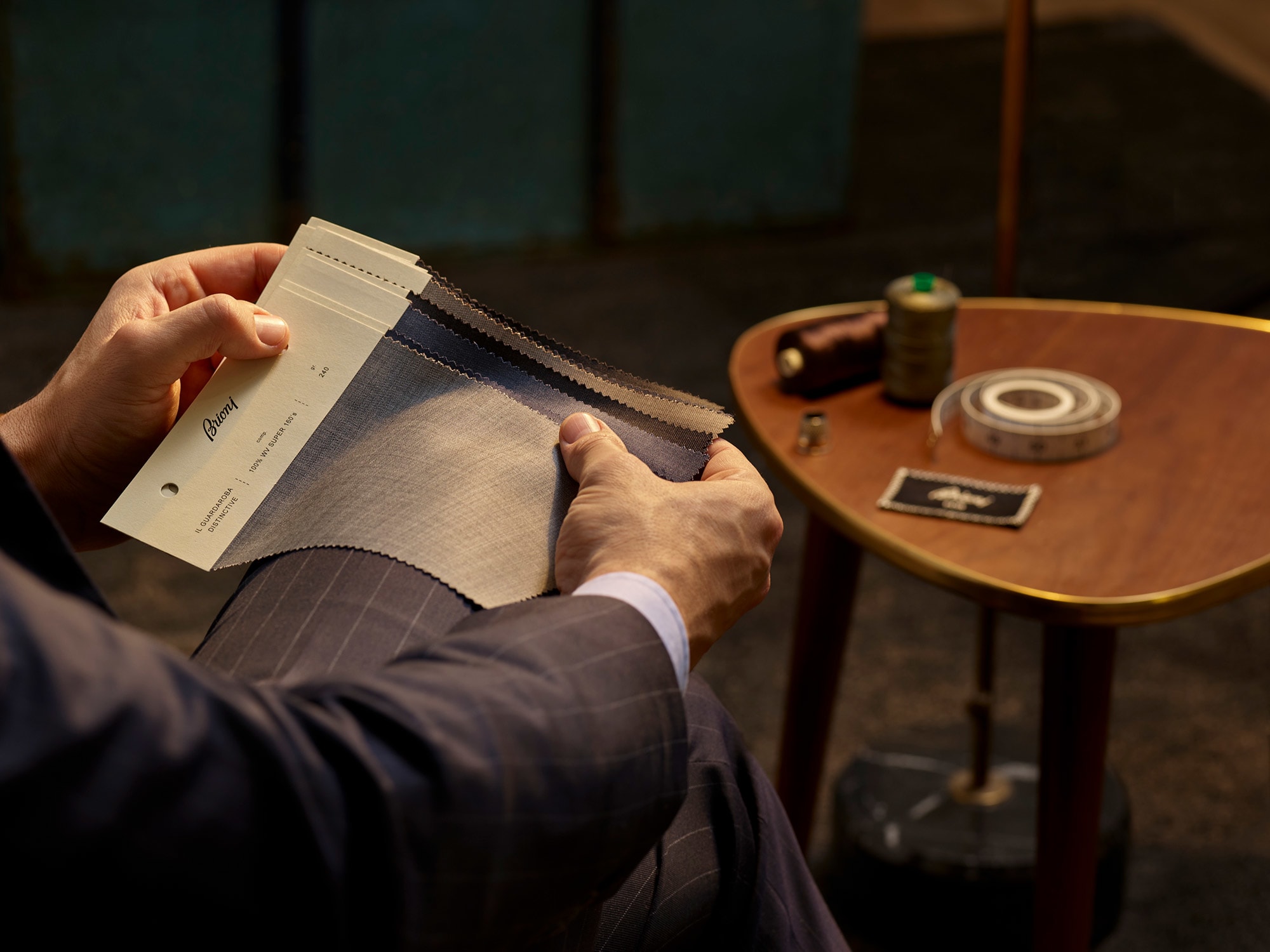 Client reviewing grey and navy fabric swatches during a Brioni bespoke appointment.
