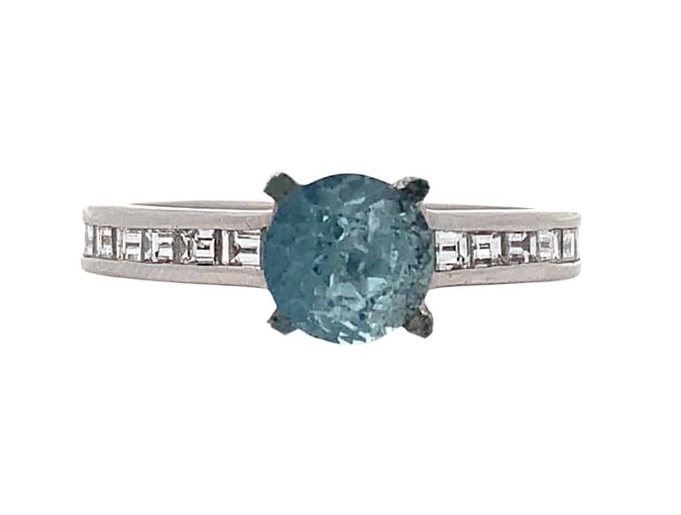 Discovers the exquisite beauty of this elegant blue aquamarine and diamond gemstone ring. Featuring a stunning central aquamarine 1.25ct round cut stone surrounded by baguette diamonds 0.69ct G VS1 sparkling accents.