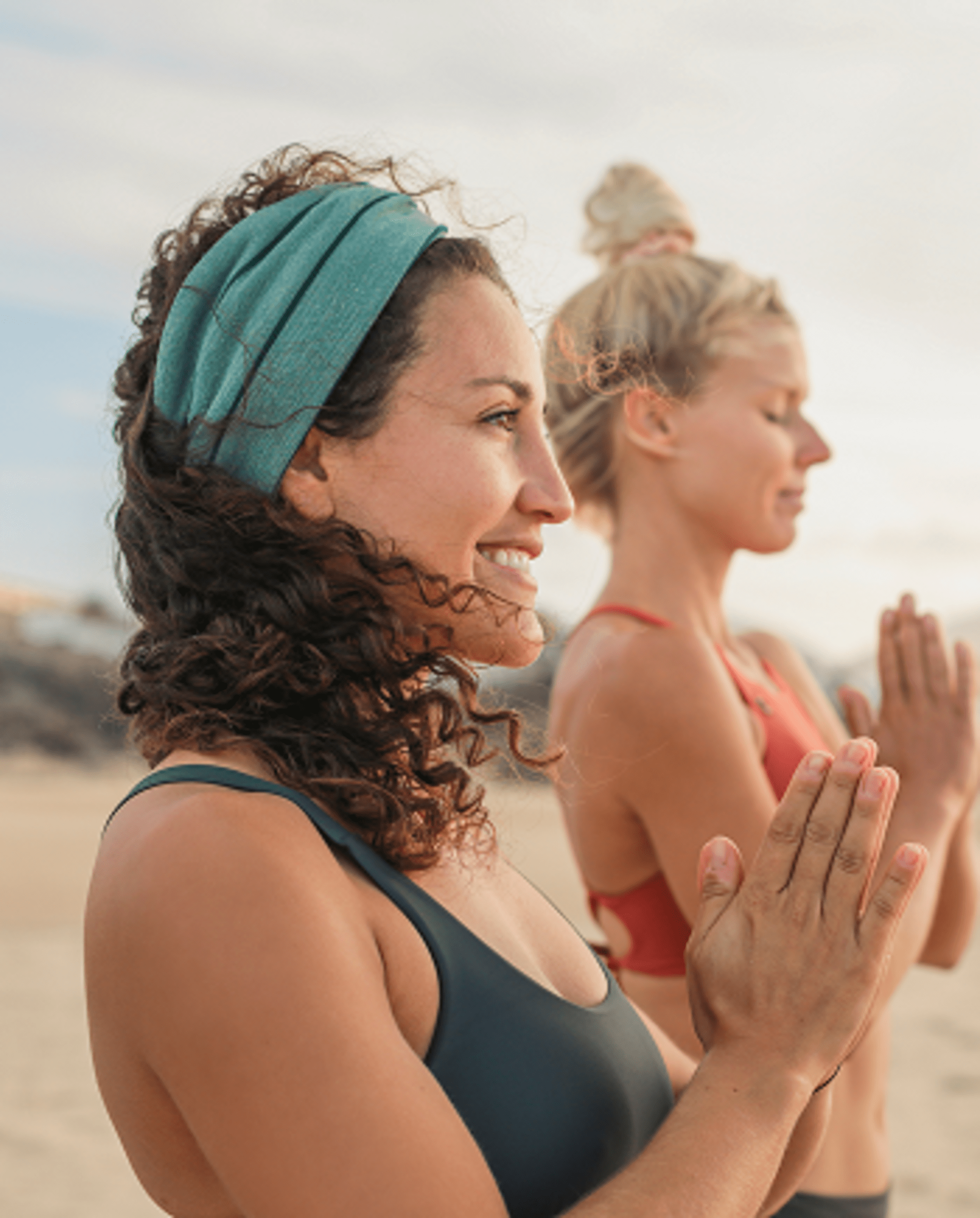 Two women doing yoga on the beach