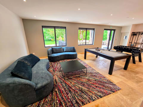 Espace détente avec billard, baby-foot et canapés dans le salon