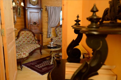 Chambre Méridien de l'Auberge Nemoz avec mobilier d'époque, fauteuil fleuri et accents de laiton sous une lumière chaleureuse