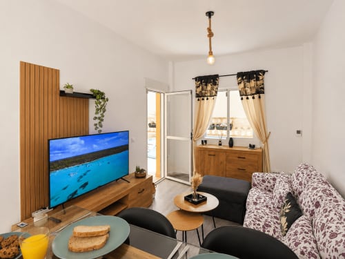 Luminosa sala de estar con televisor, sofá estampado y vistas al balcón en Apartamentos El Calón Playa, Cuevas del Almanzora