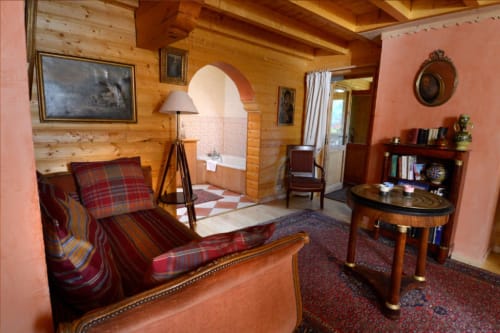 Chambre mauresque à l'Auberge Nemoz avec sièges écossais rouges, poutres en bois, porte voûtée vers baignoire et vues sur les montagnes
