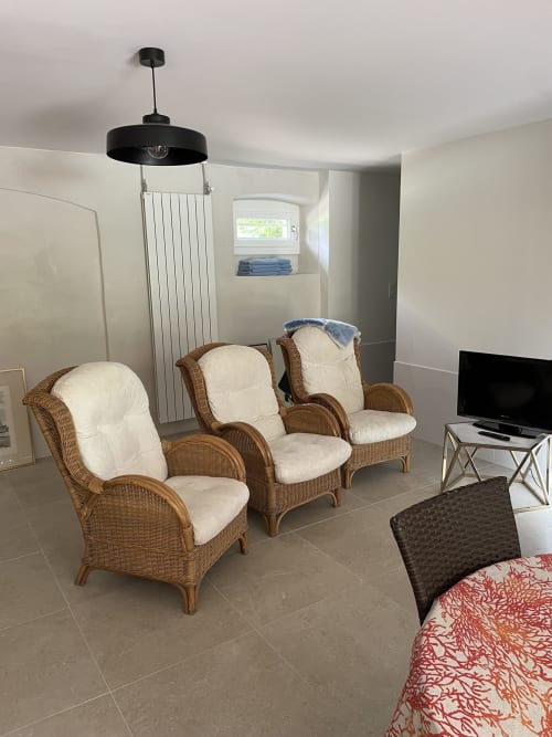 Coin salon douillet du loft Les Pratges B&B à Figeac, avec fauteuils en osier et TV écran plat