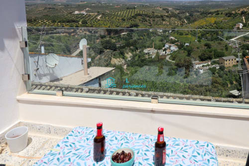 Vista montañosa desde Casa Casa en paisaje rural con olivares, muro de piedra y refrescos en la terraza