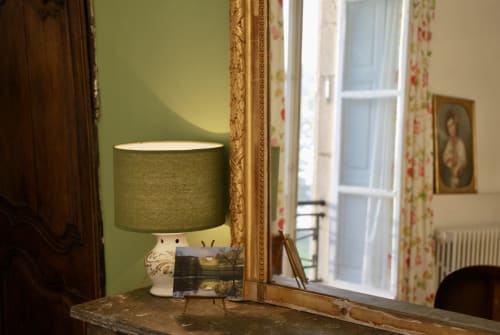 Chambre aux murs verts du Château de Vaux Morvan avec lampe, miroir encadré et portes donnant sur le jardin