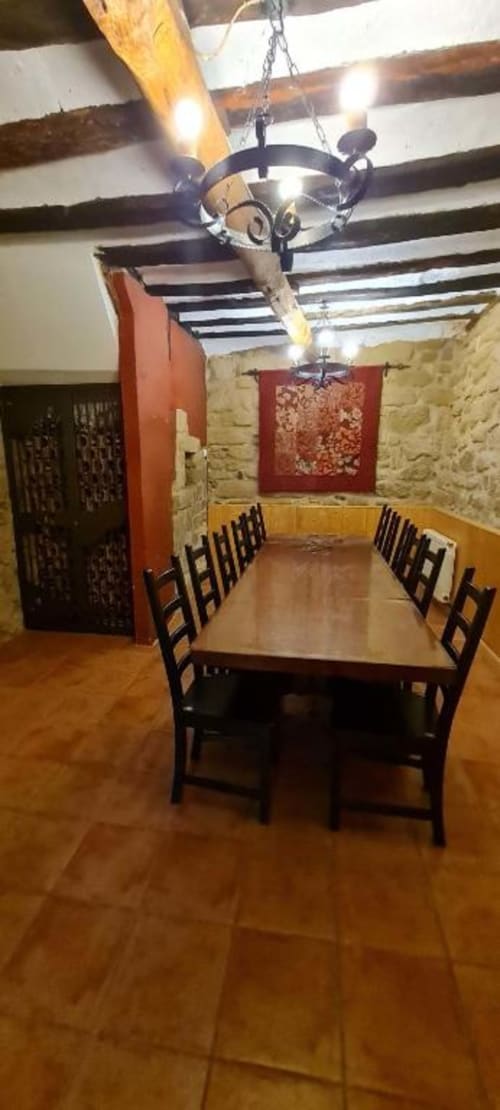 Comedor rústico en Casas Rurales La Viña con vigas de madera, muros de piedra y lámpara de hierro forjado