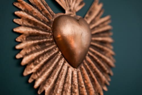 Sculpture en bronze en forme de cœur aux ailes rayonnantes sur mur turquoise dans l'appartement Escapade Chic aux Séjours Ardennais