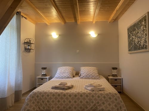 Chambre accueillante à la Maison d'hôtes Le Cocon De Curson à Chanos-Curson avec plafond en bois, lit double, tables de nuit et appliques murales