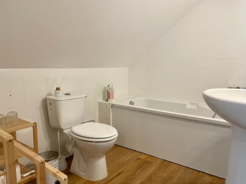 Salle de bain lumineuse avec carrelage blanc, toilettes, baignoire et vasque ronde au gîte Château de Vaux Morvan à Étang sur
