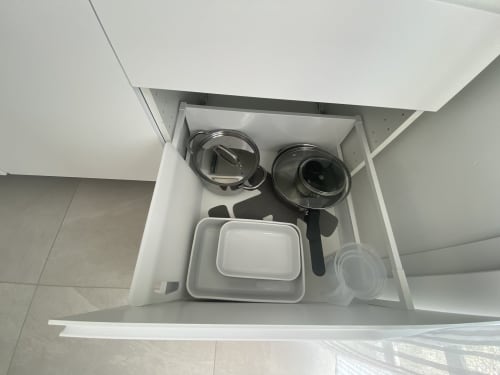 Open kitchen drawer in La Maison Blanche apartment showing cookware, storage containers, and kitchen utensils