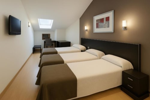 Habitación triple en Hotel Villa de Cacabelos con tres camas individuales, TV de pantalla plana, escritorio y comodidades modernas en Cacabelos
