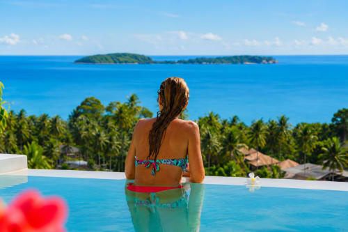 Woman in infinity pool overlooking turquoise sea and islands at Indigo Villa Samui, Ko Samui