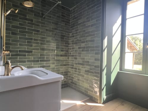 Salle de bains moderne avec carrelage vert foncé, lavabo blanc, robinetterie laiton et grande fenêtre de la chambre Charette à La