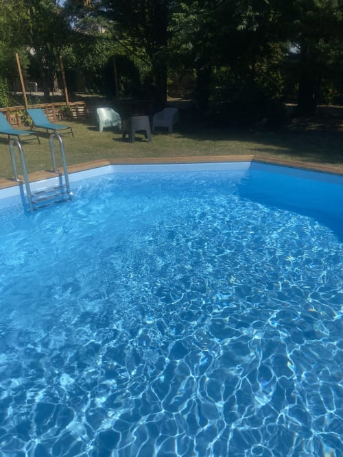 Piscine cristalline du gîte Le Cocon De Curson à Chanos-Curson, entourée de verdure et de jardins luxuriants