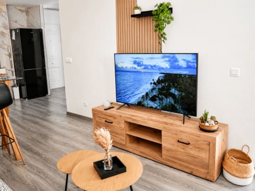 Sala moderna de Apartamentos El Calón Playa con mueble TV de madera, vista costera del océano en pantalla y decoración natural