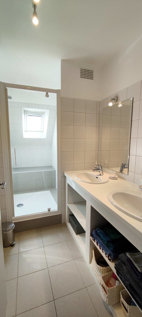 Salle de bain moderne de la villa Mer et Maisons avec doubles vasques, douche italienne et rangements à La Trinité sur Mer
