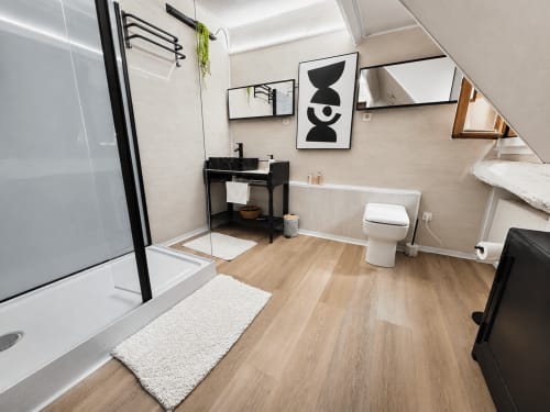 Salle de bains attenante chaleureuse au Domaine Valenquercy BnB avec lavabo noir, toilettes, douche, sol en bois et décoration moderne