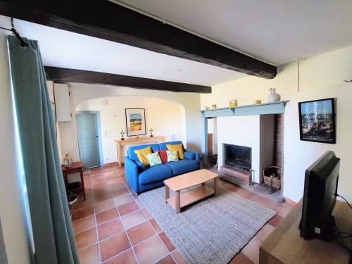 Bright living room in Orchids cottage at Les Gites de Campardon with blue sofa, fireplace, and terra cotta tiles