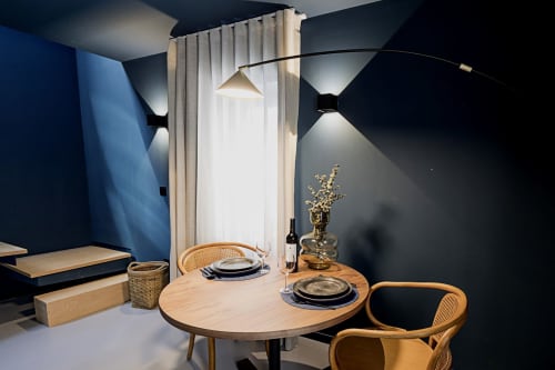 Área de refeições moderna do hotel Porto com mesa redonda de madeira, cadeiras de vime e paredes elegantes azul escuro