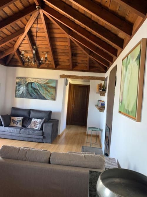 Sala de estar de villa moderna con vigas de madera vista, sofá gris, obras de arte y pisos de madera en Rural La Palma