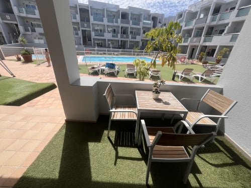 Shaded terrace with dining table overlooking Corralejo Sol y Sal apartment pool and grounds