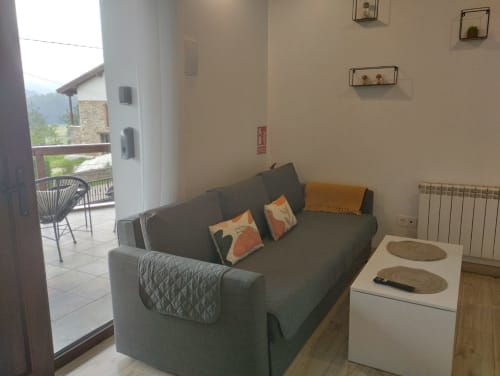 Acogedora sala de estar del apartamento Dobra en El Respigu, Cangas de Onís, con sofá gris, vistas a la montaña y comodidades modernas