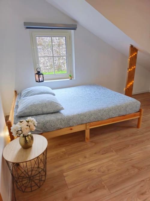 Chambre cosy sous les toits aux Gîtes Saint Valery En Caux avec lit en bois, lumière naturelle par la lucarne, plancher en bois dur