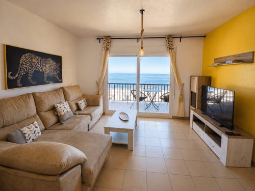Apartamento con vistas al mar, sofá beige, pared amarilla y vistas panorámicas al océano desde balcón en Cuevas del Almanzora